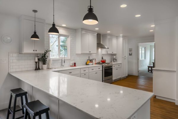 Classy kitchen with white cabinets, white countertops, and white tile