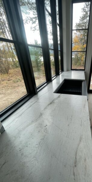 Long quartzite countertop with dark framed windows